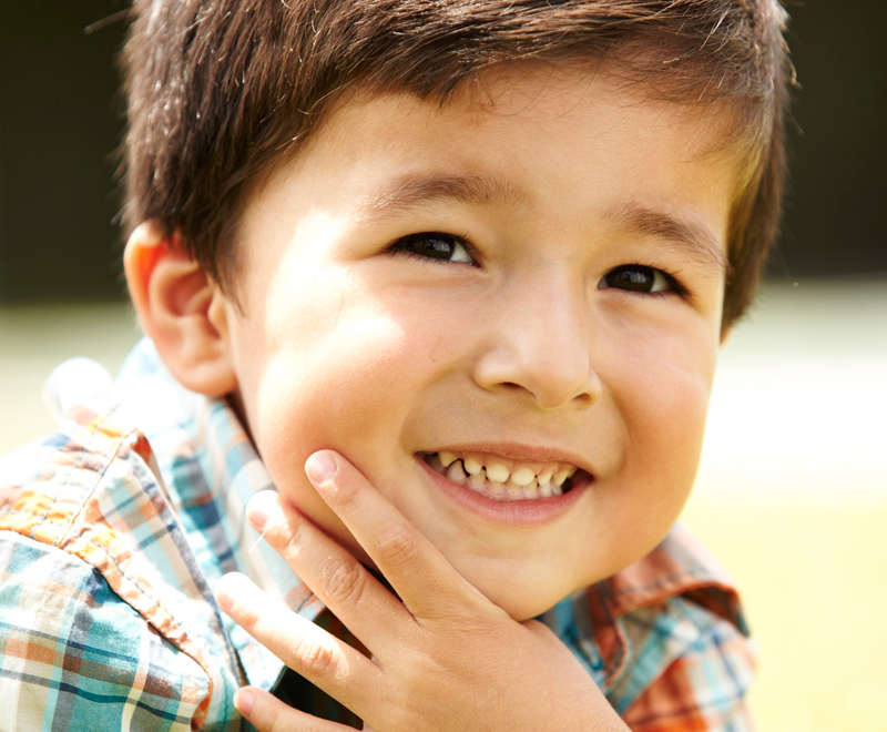 Young boy with hands around chin smiling